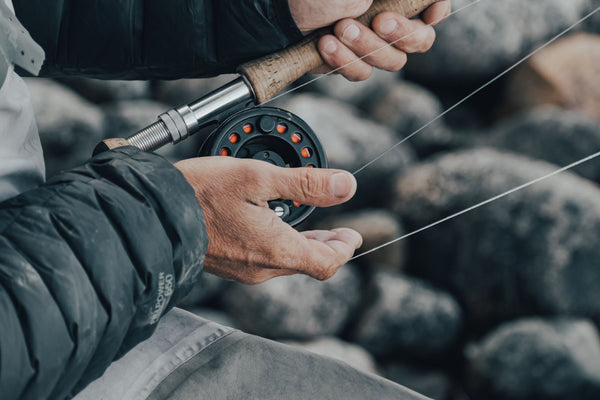 Mãos de pescador segurando vara de pesca